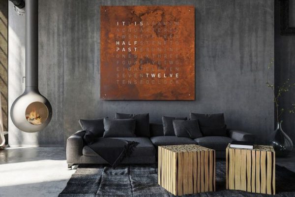 QLOCKTWO woordklok in roeststaal boven een bank in een woonkamer