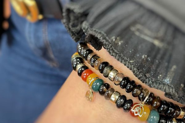 Pols met Y&G armbanden met donkere edelsteenkralen en goud