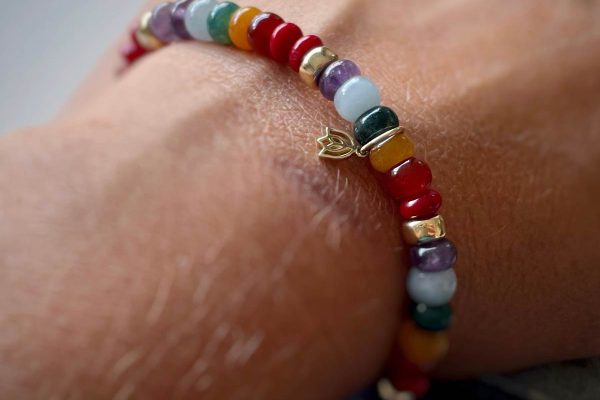 Pols met Y&G armband met kleurige edelsteenkralen