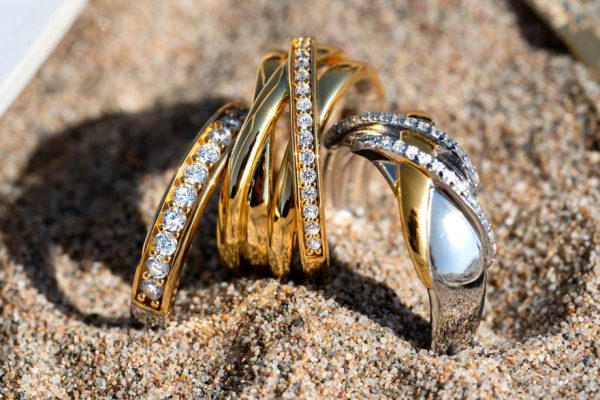 Gouden en zilveren Zinzi ringen met heldere stenen op zand