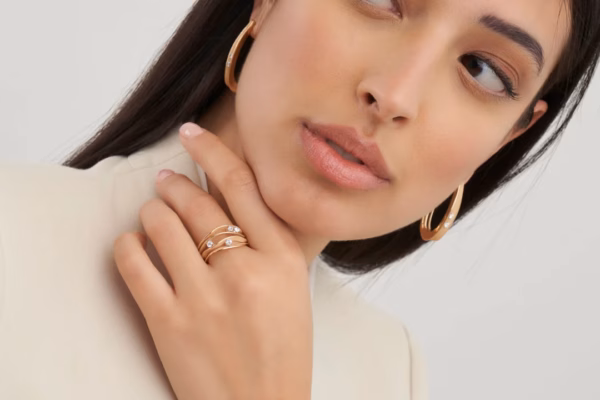 Vrouw draagt roségouden creolen, gestapelde ringen en een armband met diamant van Cammilli Firenze